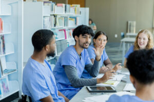 Pharm tech talking at a table with a group of pharm techs.